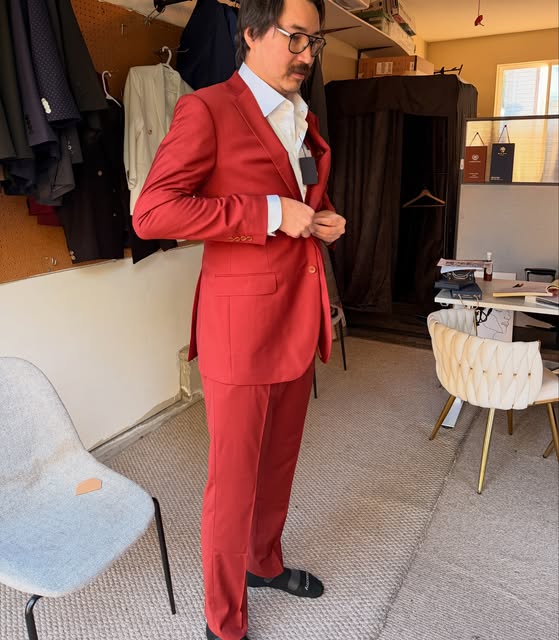 Man in a bold red custom suit standing in the City Custom Suits showroom